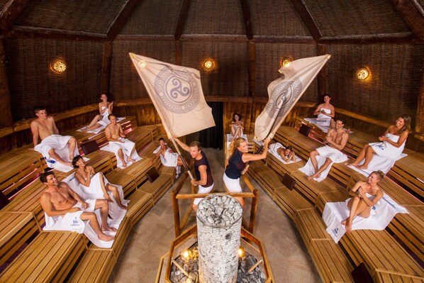 A sauna with wooden benches arranged in a circular pattern around a central fire pit.