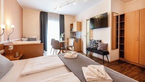 A hotel room with a bed, bedside table, desk, chair, and a TV mounted on the wall. - Gästehaus Zehmerhof (Walpertskirchen)