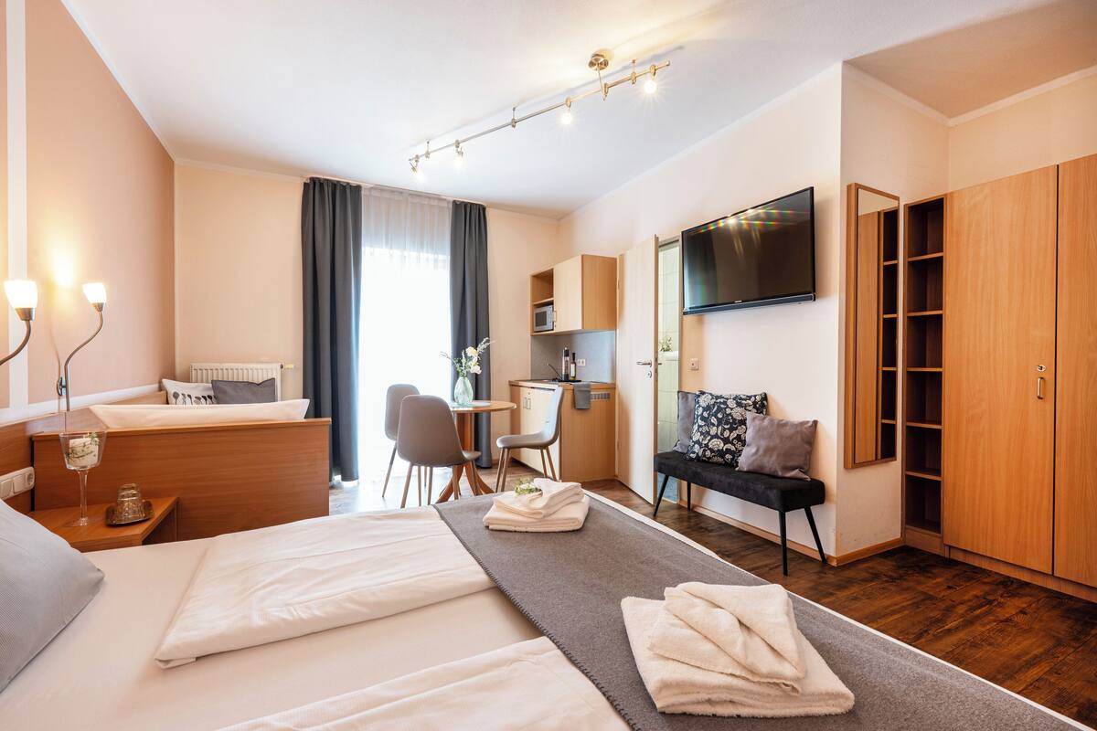 Une chambre d’hôtel équipée d’un lit, d’une table de chevet, d’un bureau, d’une chaise et d’un téléviseur fixé au mur.