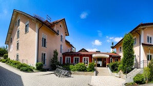 A two-story building with a reception area, a staircase, and a bicycle parked in front. - Gästehaus Zehmerhof (Walpertskirchen)