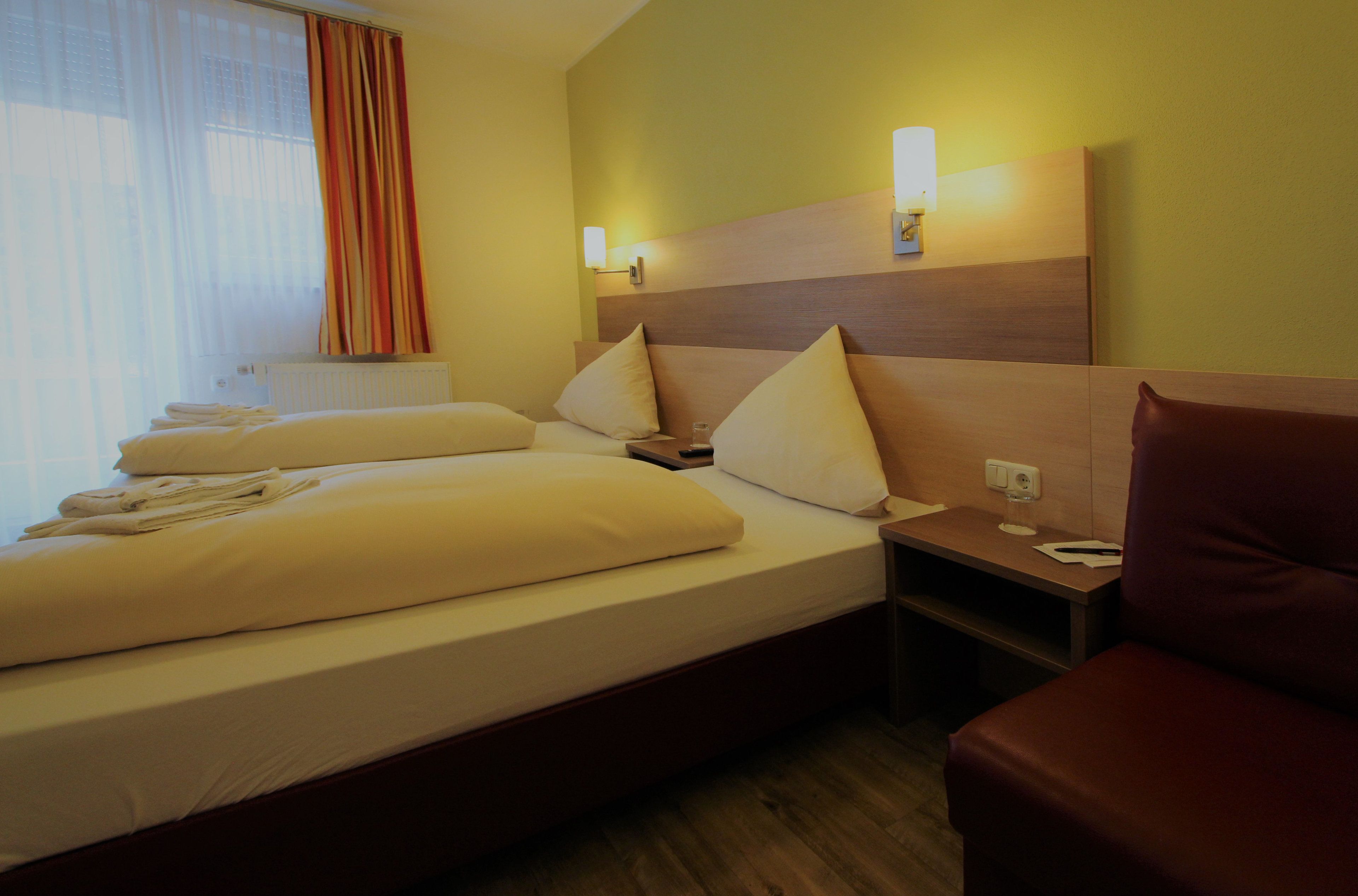A hotel room with a large bed, two bedside tables, a nightstand, and a seating area.