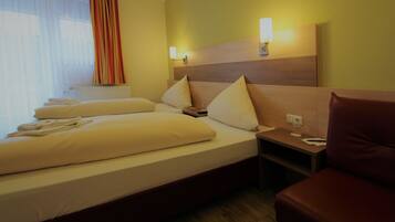 A hotel room with a large bed, two bedside tables, a nightstand, and a seating area.