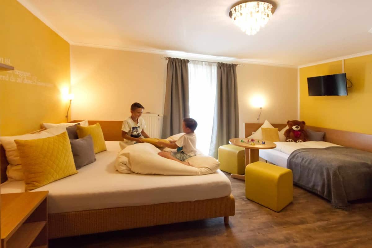 Une chambre d’hôtel avec deux lits, une petite table et un ours en peluche.