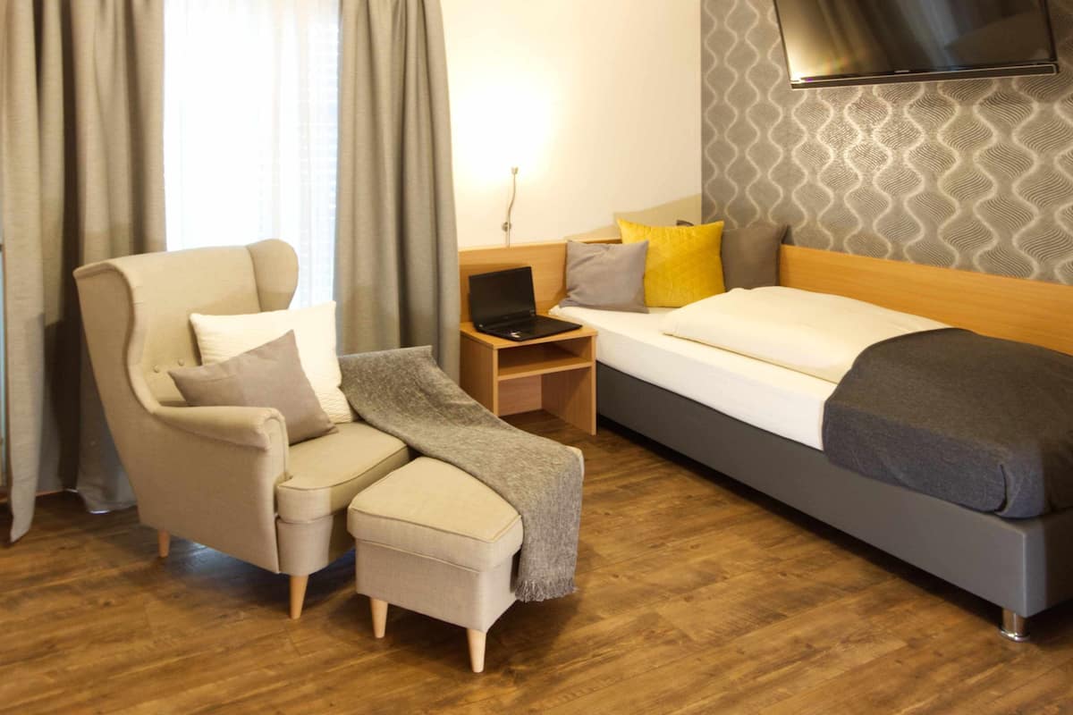 Une chambre d’hôtel équipée d’un lit, d’un bureau avec un ordinateur portable, d’une chaise et d’un téléviseur fixé au mur.