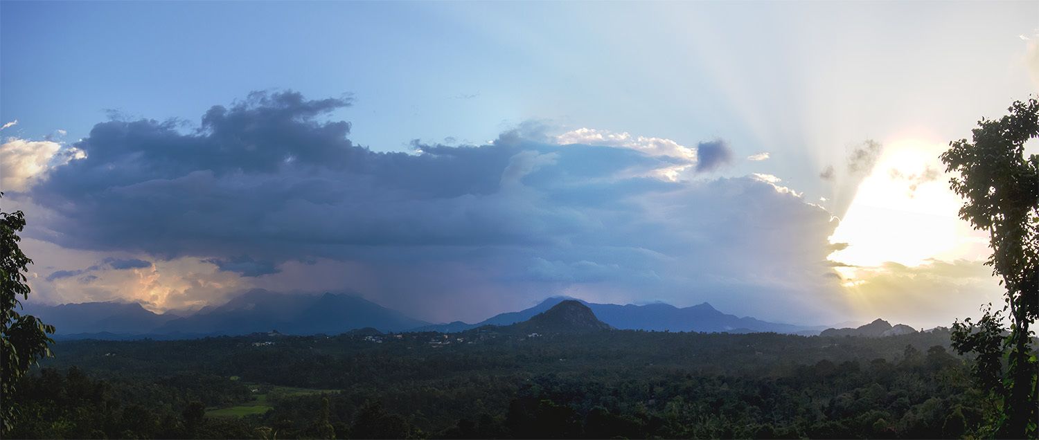 Un paysage montagneux, avec un ciel dégagé et des rayons de soleil perçant les nuages.
