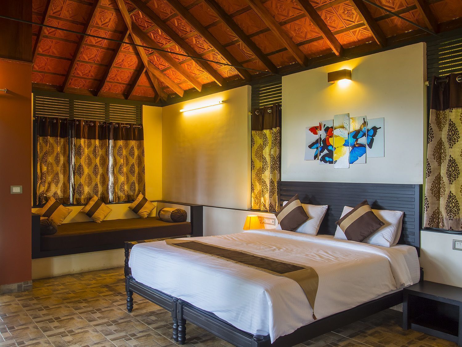 A bedroom with a bed, bedside tables, a headboard, a window with curtains, and a wall-mounted artwork.