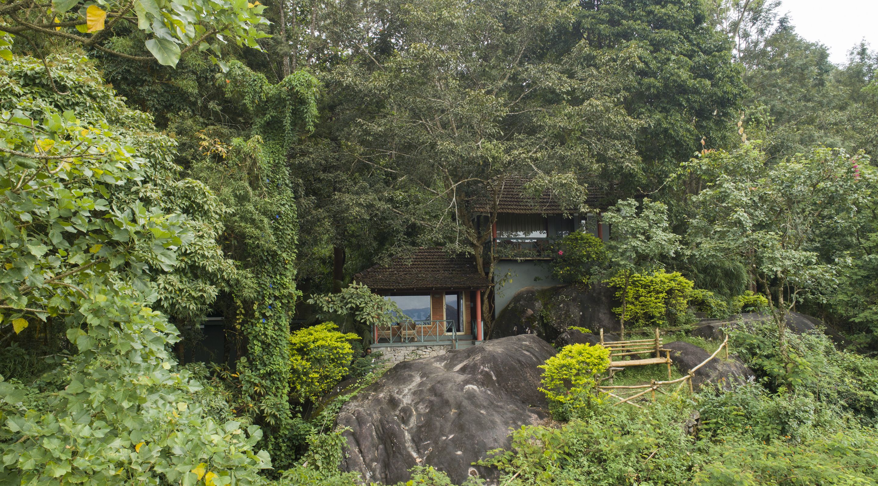 A traditional building nestled among lush greenery, with a stone pathway leading to it.