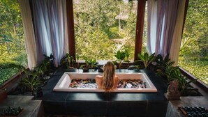 A woman sitting in a bathtub with a view of lush greenery outside. - Pilgrimage Wellness Retreat – part of Pilgrimage Village Resort & Spa (Hue)
