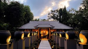 A traditional Japanese-style building with a wooden walkway leading to the entrance, surrounded by large water features. - Pilgrimage Wellness Retreat – part of Pilgrimage Village Resort & Spa (Hue)