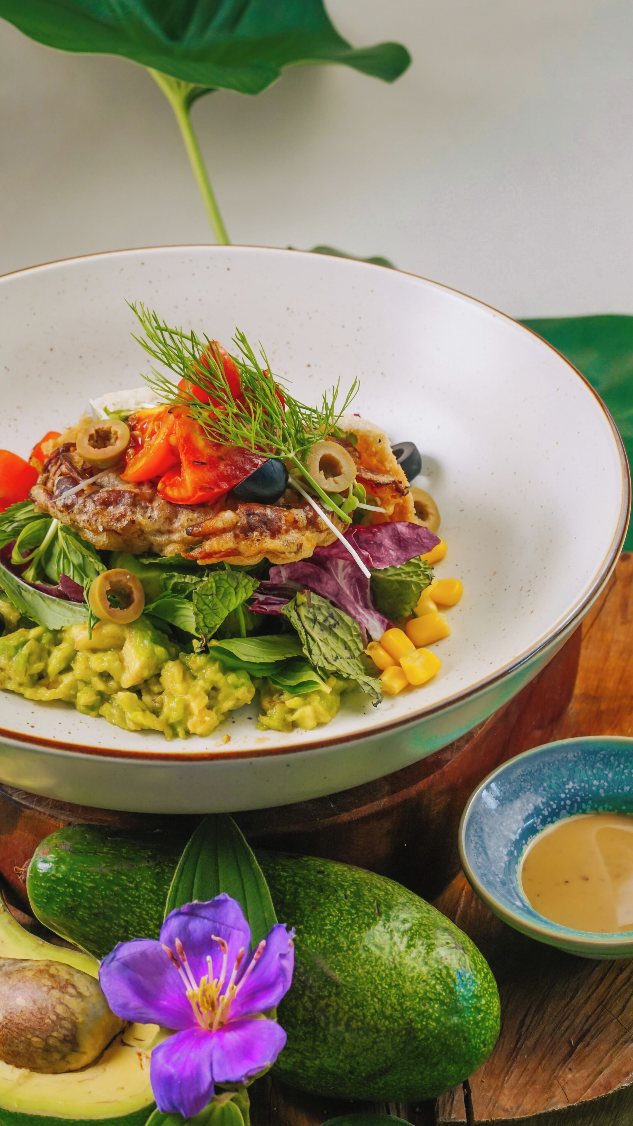 Un plato de comida con diversos vegetales y una flor.