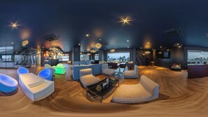 Un área de estar moderna con sofás y sillones, una mesita de centro y vistas a la ciudad.