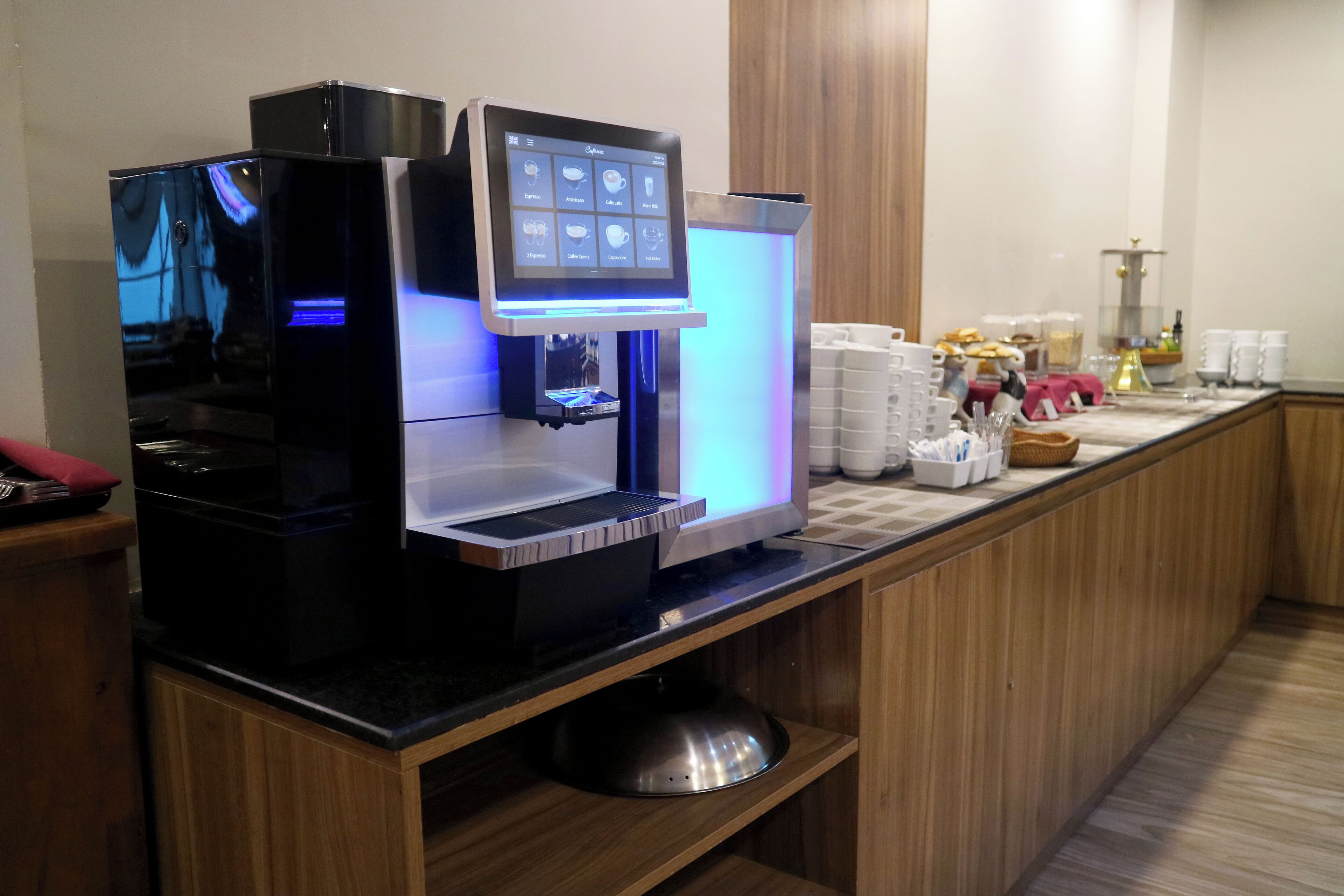 A self-service coffee machine with a digital display, a coffee dispenser, and a variety of coffee options.
