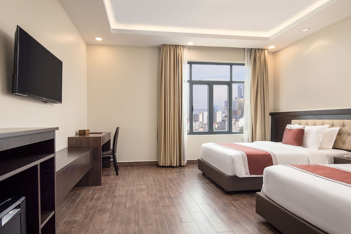 Une chambre d’hôtel avec un lit, un bureau, une télévision et une fenêtre avec des rideaux.
