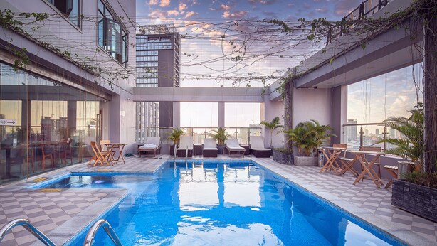 Una piscina en la azotea con sillones de descanso y plantas en macetas.