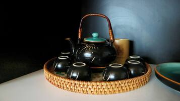 A tea set with a teapot and cups arranged on a woven tray.