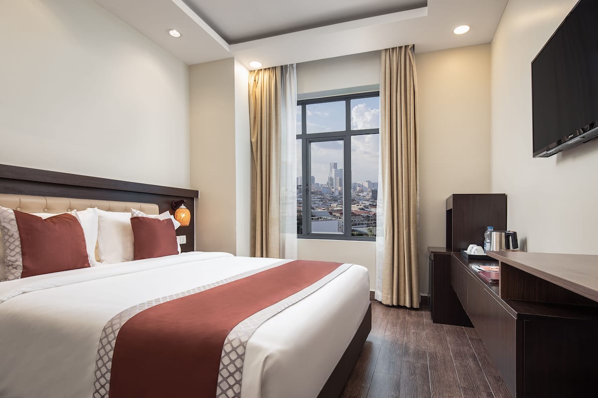 Une chambre d’hôtel avec un grand lit, un bureau, une télévision et une fenêtre donnant sur la ville.