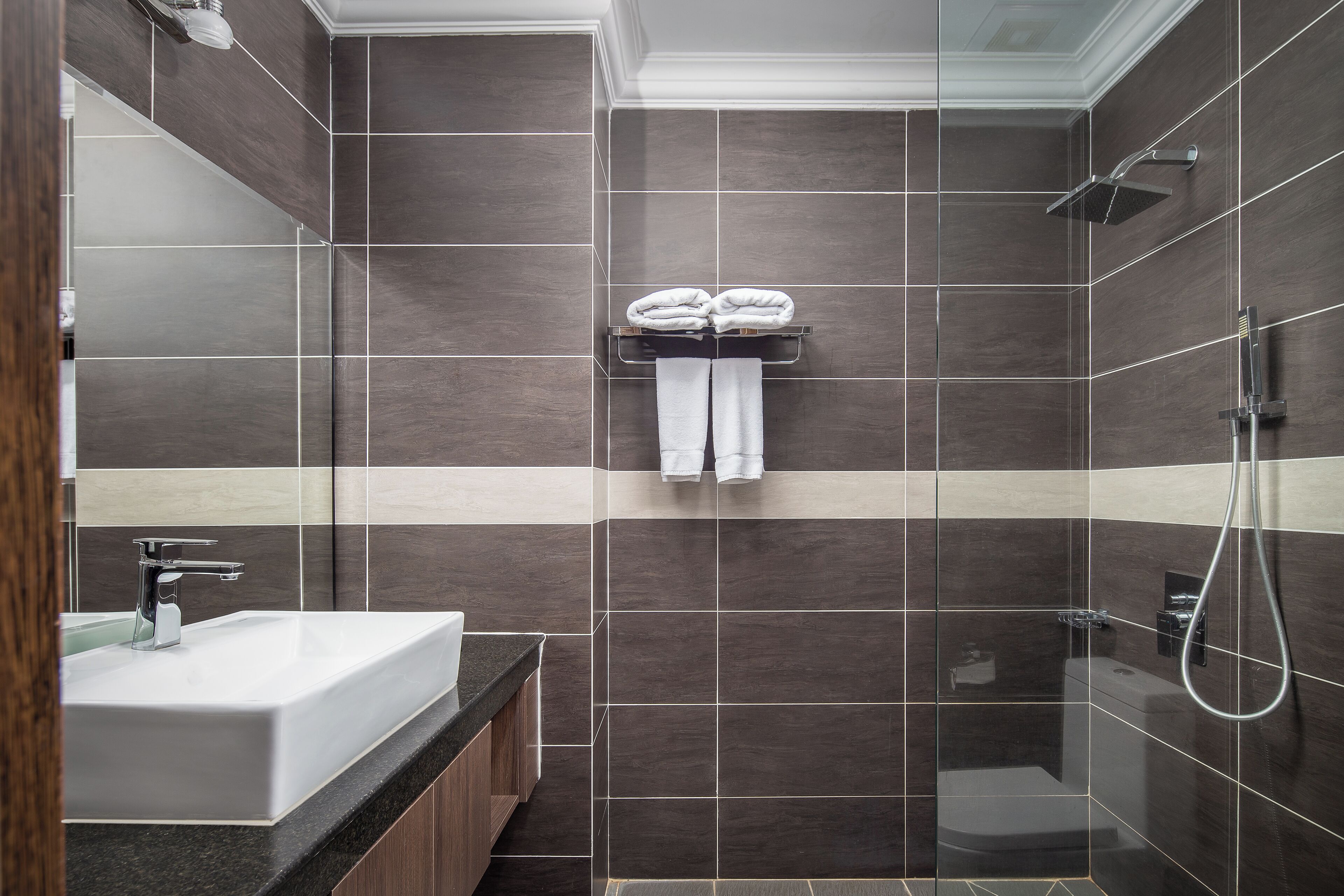 Un baño moderno con un lavamanos grande, una ducha y un perchero con dos toallas.