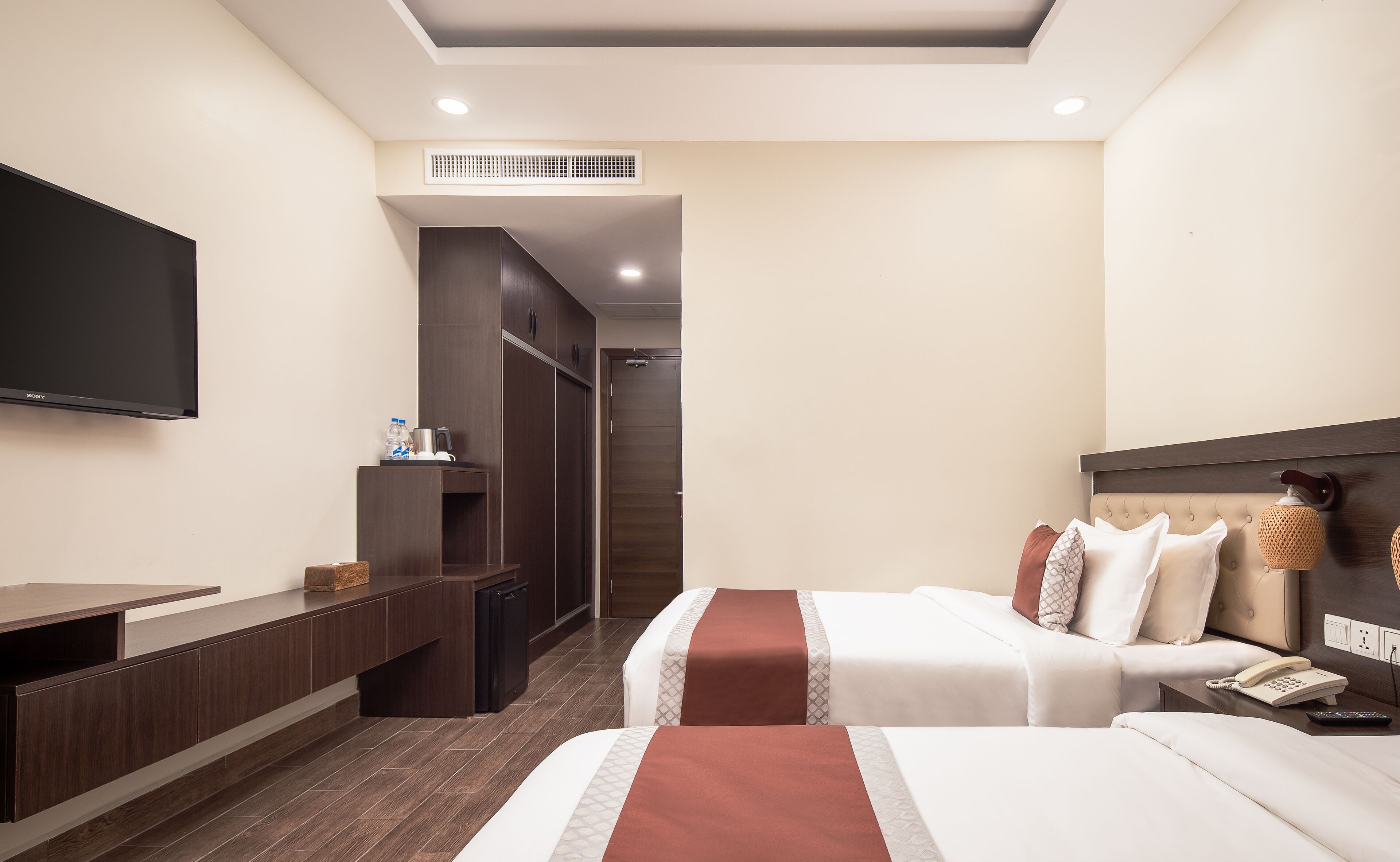 Une chambre d’hôtel équipée d’une télévision à écran plat, d’un minibar, d’un bureau et d’un lit avec une tête de lit.