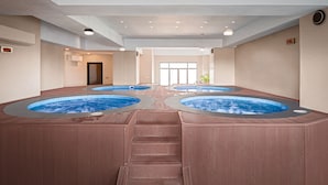 Un amplio espacio interior con piscina, varios jacuzzis y una escalera central.