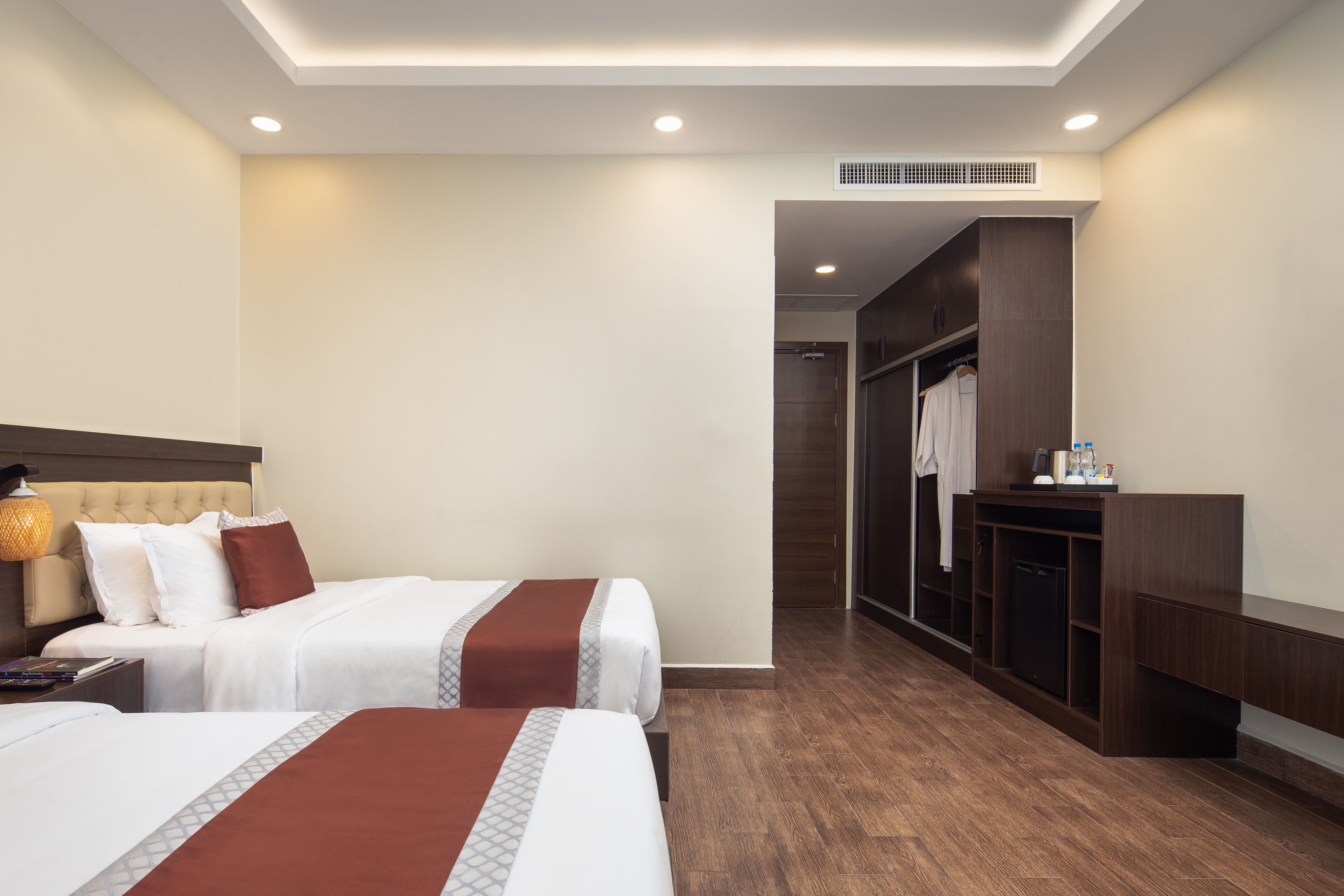 A hotel room with two beds, a wardrobe, a desk, and a nightstand.