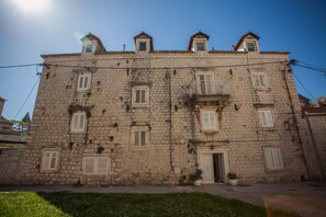 A stone building with multiple windows and a door, featuring a small balcony and a satellite dish. - Top floor apartment (Trogir)