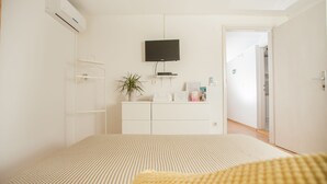A bedroom with a bed, a TV mounted on the wall, a dresser, and a plant. - Top floor apartment (Trogir)