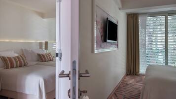 Ein Hotelzimmer mit Bett, Wandfernseher und Vorhängen am Fenster.