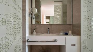 Un baño moderno con tocador, espejo, perchero y un lavamanos pequeño.