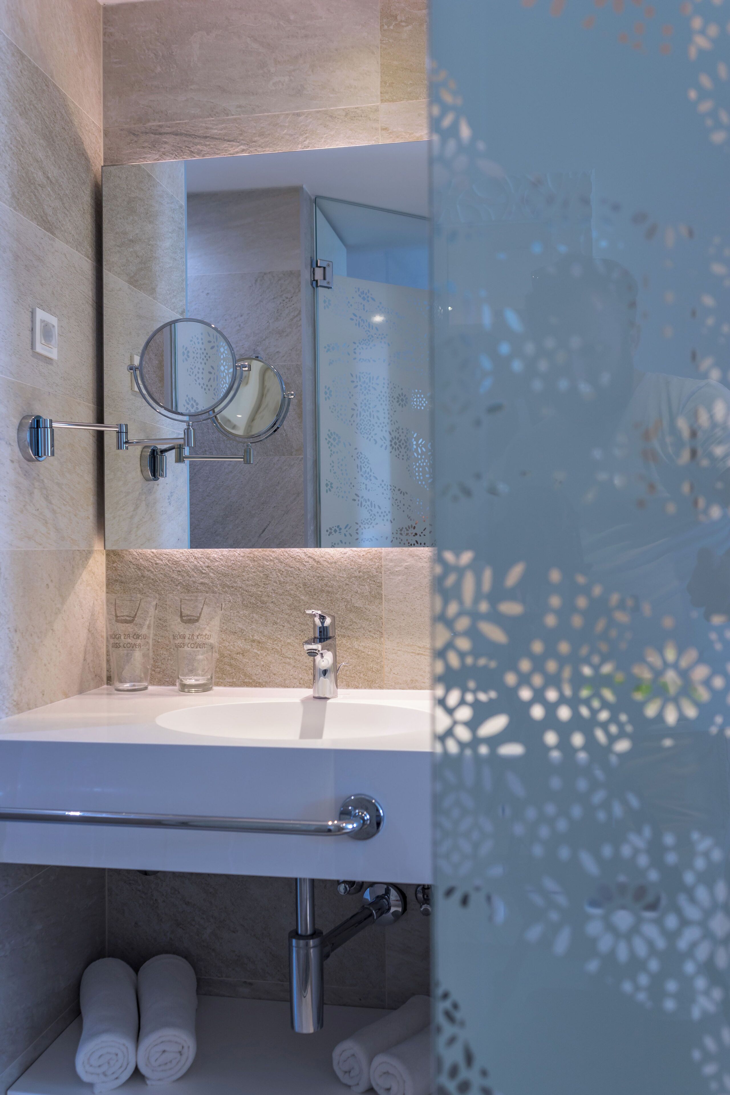 A modern bathroom with a glass shower enclosure, a built-in sink, and a towel rack.