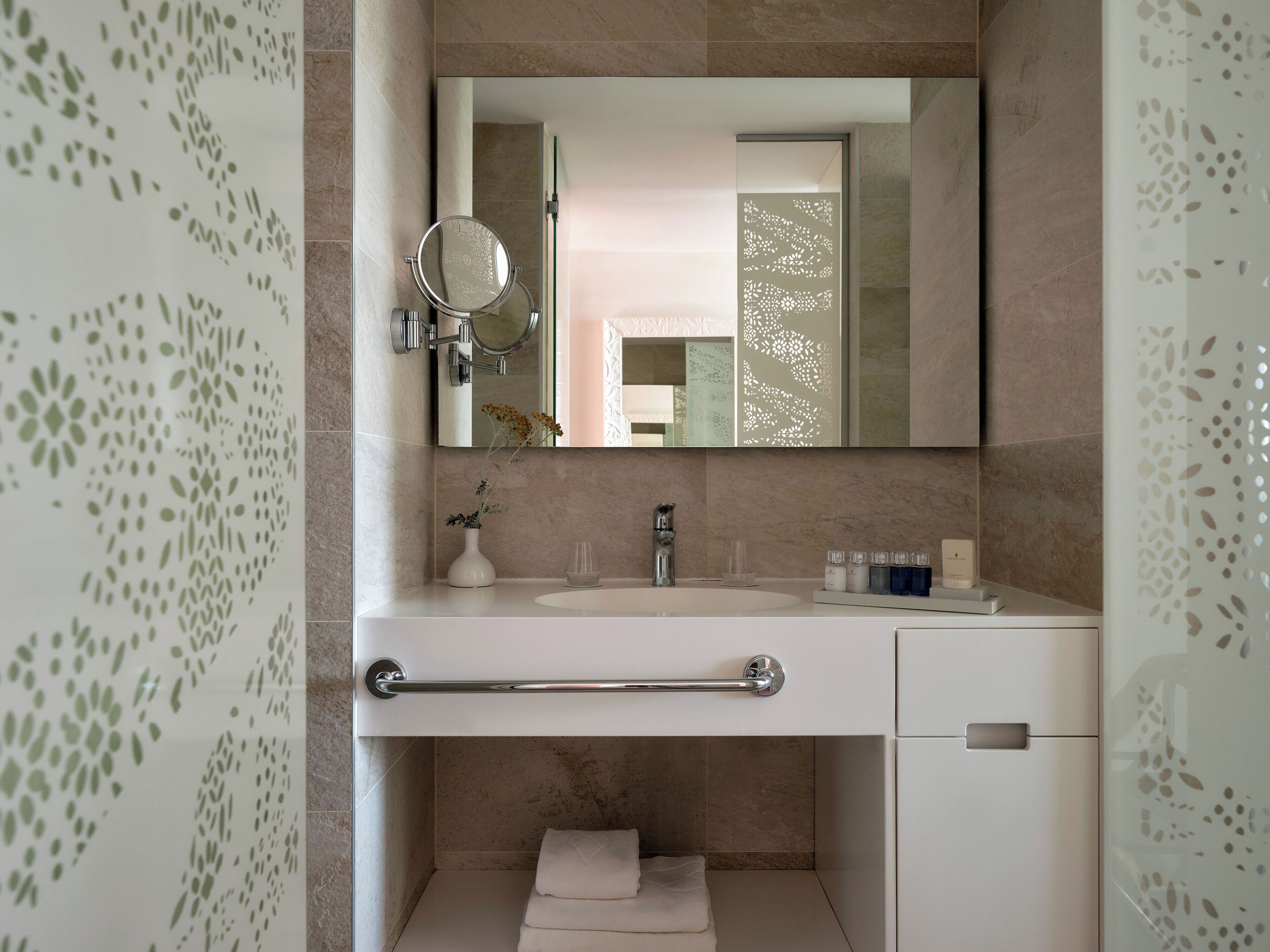 A modern bathroom with a vanity, a mirror, a towel rack, and a small sink.