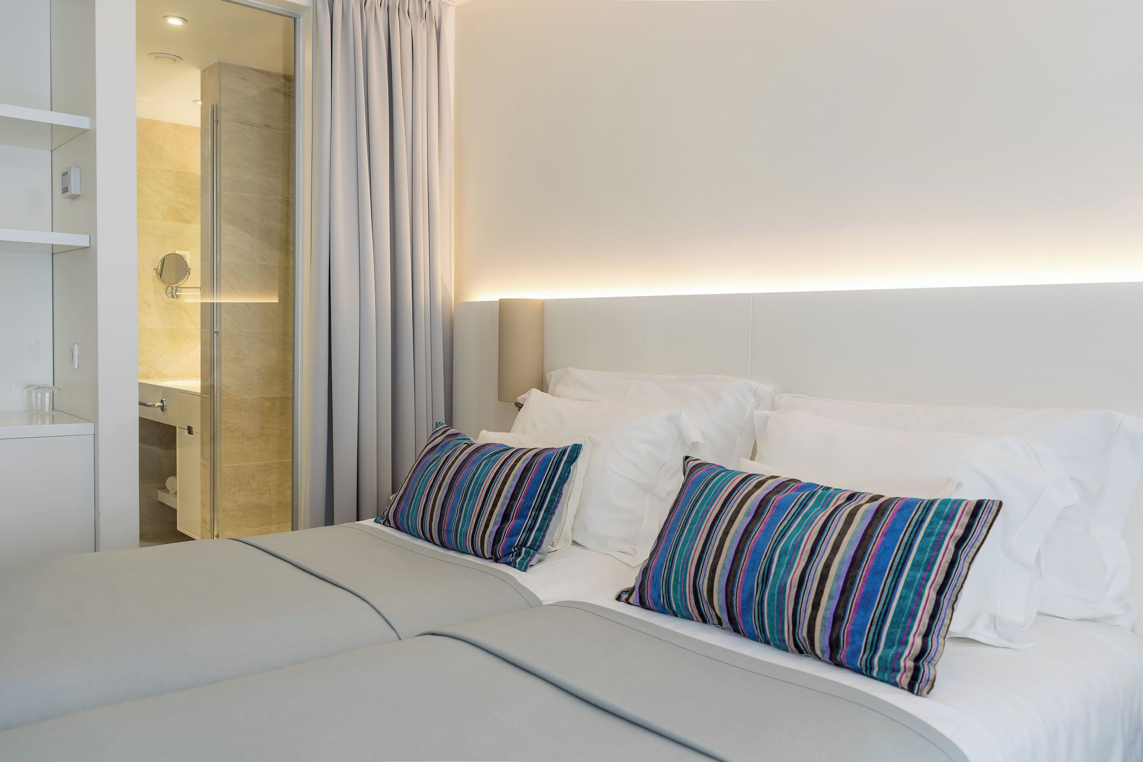 Una habitación de hotel con cama, ducha y cabecero blanco.