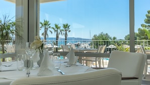 A table set for dining with a view of the sea and palm trees.
