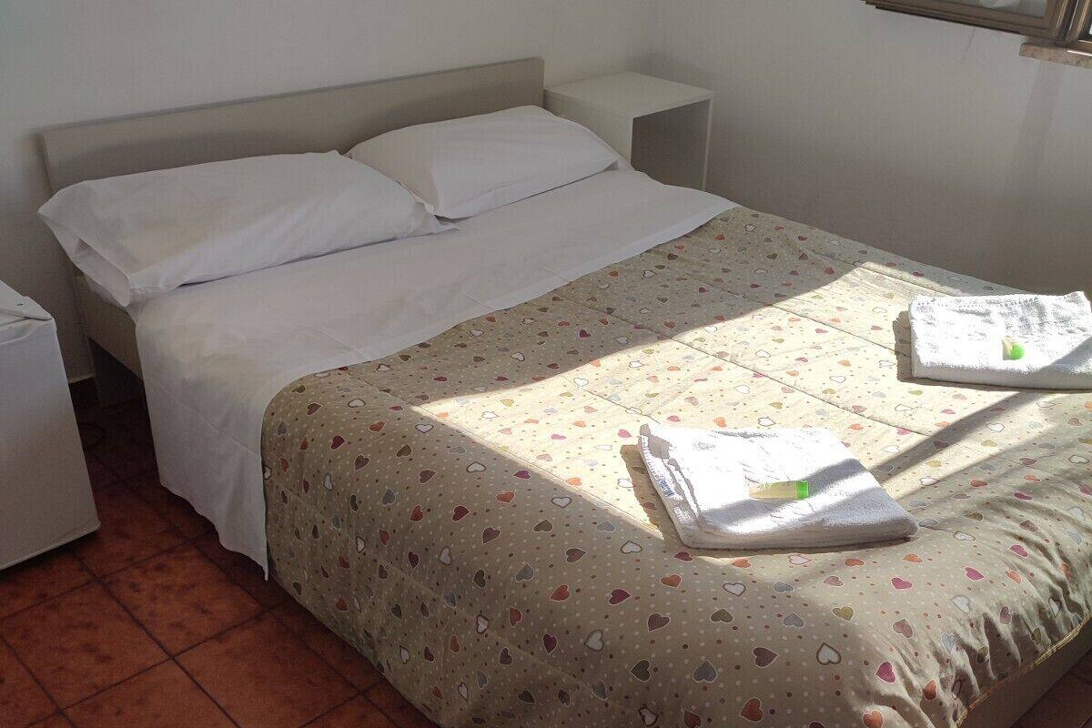 A neatly made bed with a patterned bedspread, a bedside table, and a nightstand.