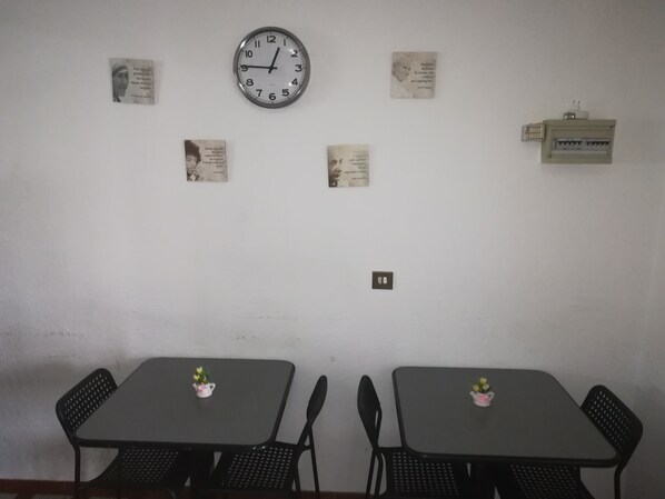 A room with two tables and chairs, a wall clock, and several framed quotes. - Albergo Italia (Reggio nell'Emilia)