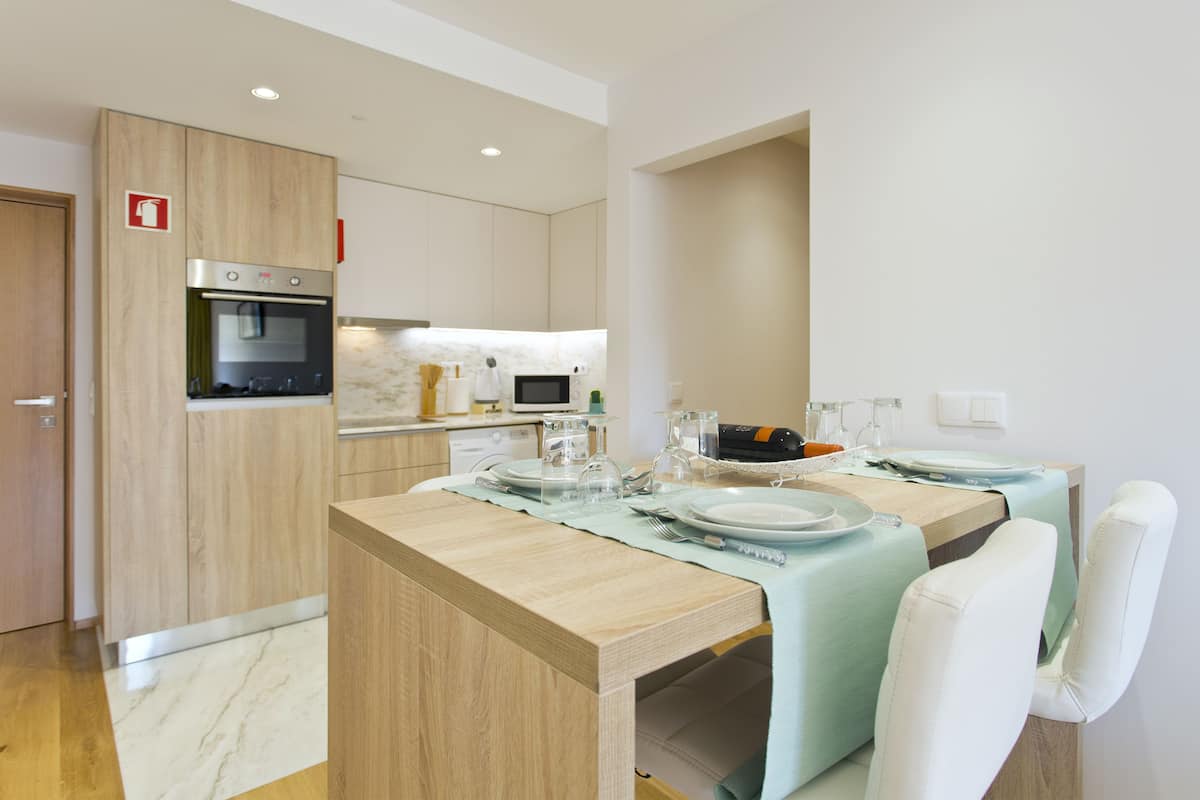 A modern kitchen with wooden cabinets, a built-in oven, and a dining area with a table set for two.