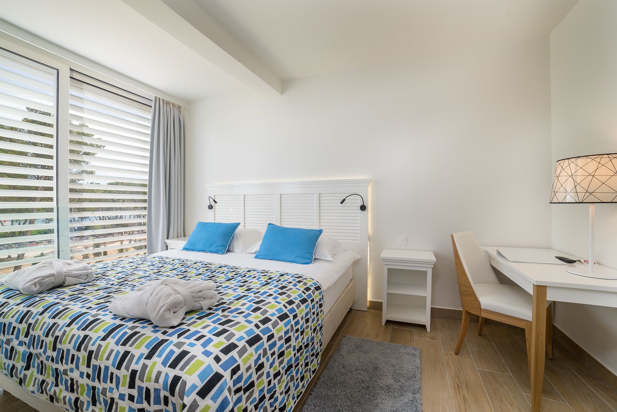 A hotel room with a bed, a desk, and a chair.