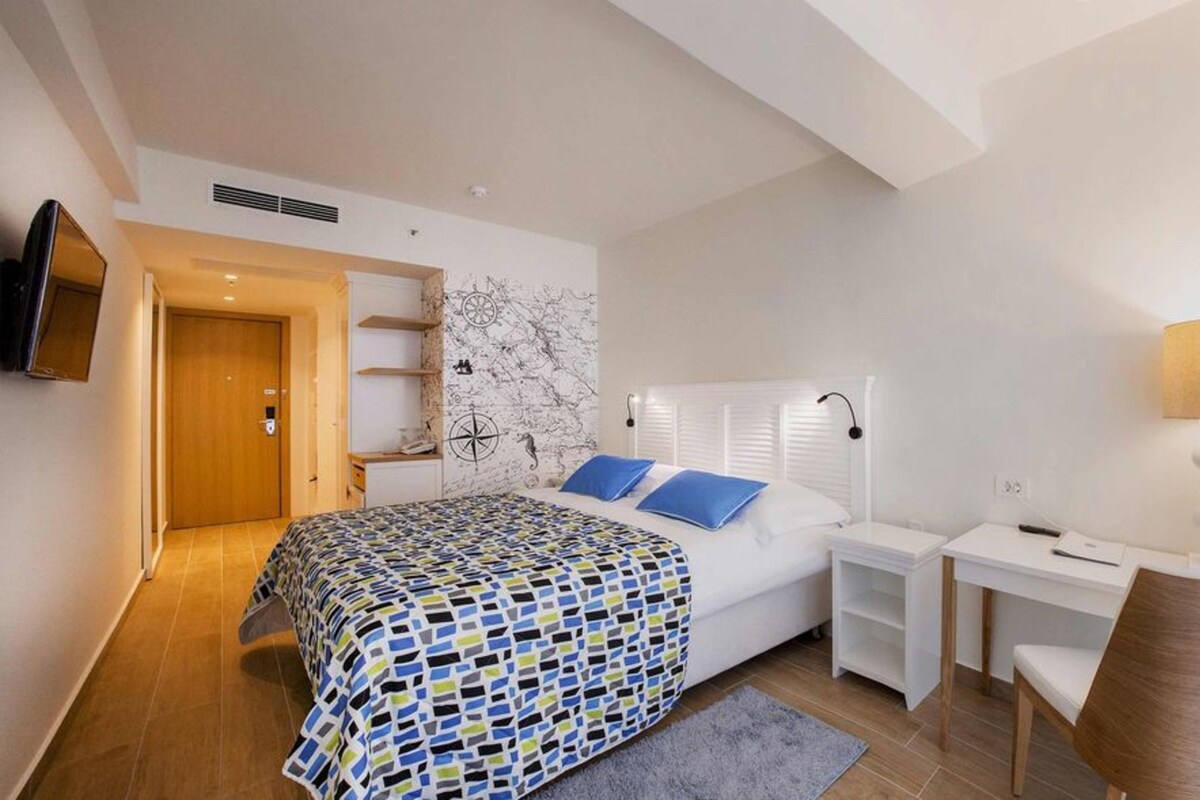 Un dormitorio con una cama, un escritorio, una silla, un televisor y un mapa en la pared.