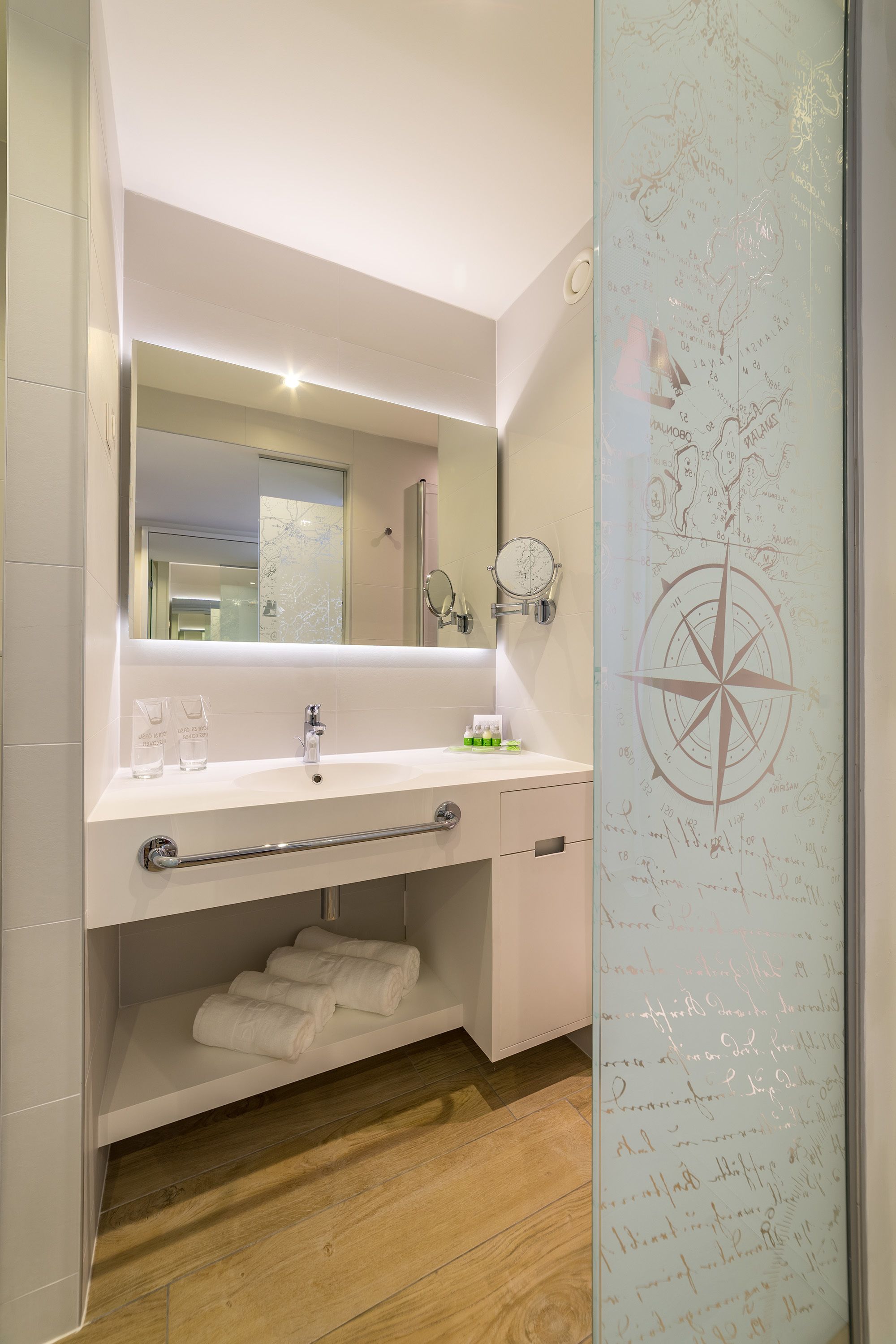 A modern bathroom with a large mirror, white sink, and a towel rack.