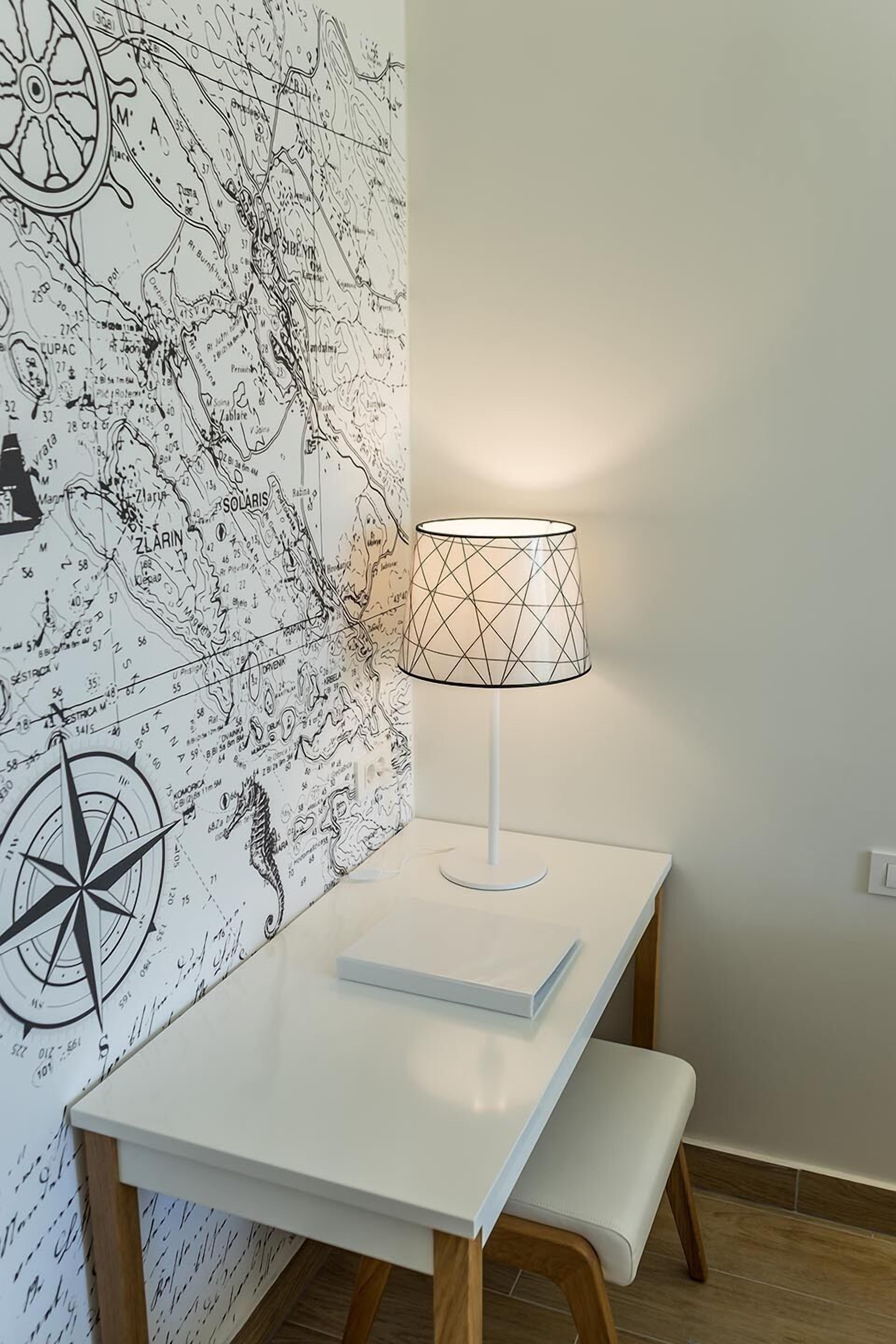 A white table with a lamp and a map wallpaper.