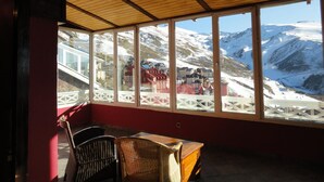 A room with a view of snow-covered mountains, a wooden ceiling, and a table with chairs. - Hotel Reino Nevado (Monachil)