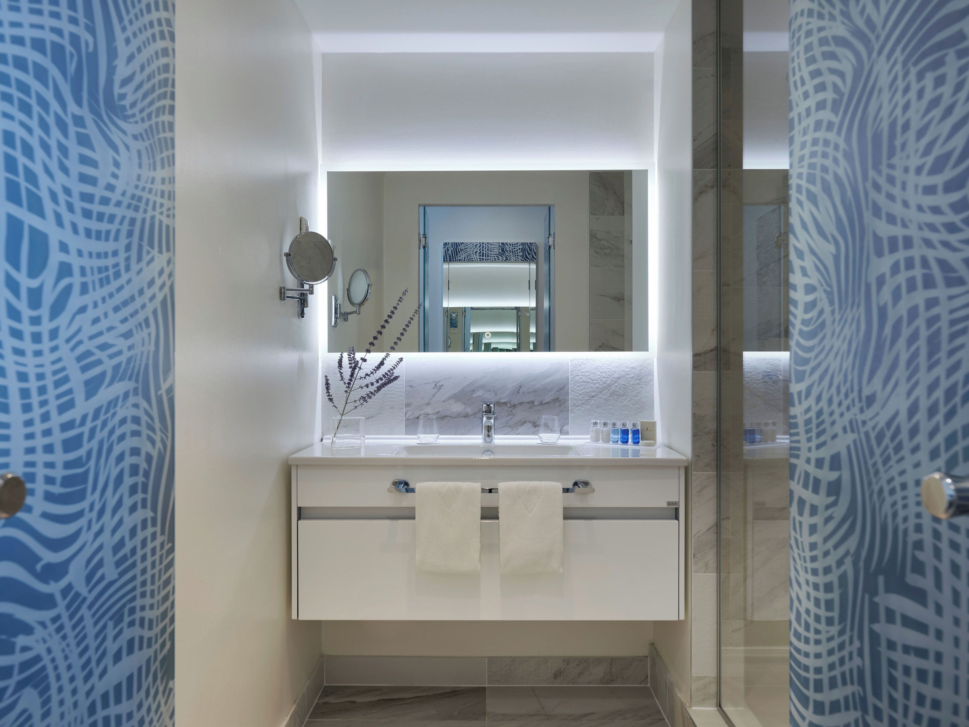 Un baño moderno con un lavabo de mármol, un espejo y una zona de ducha.