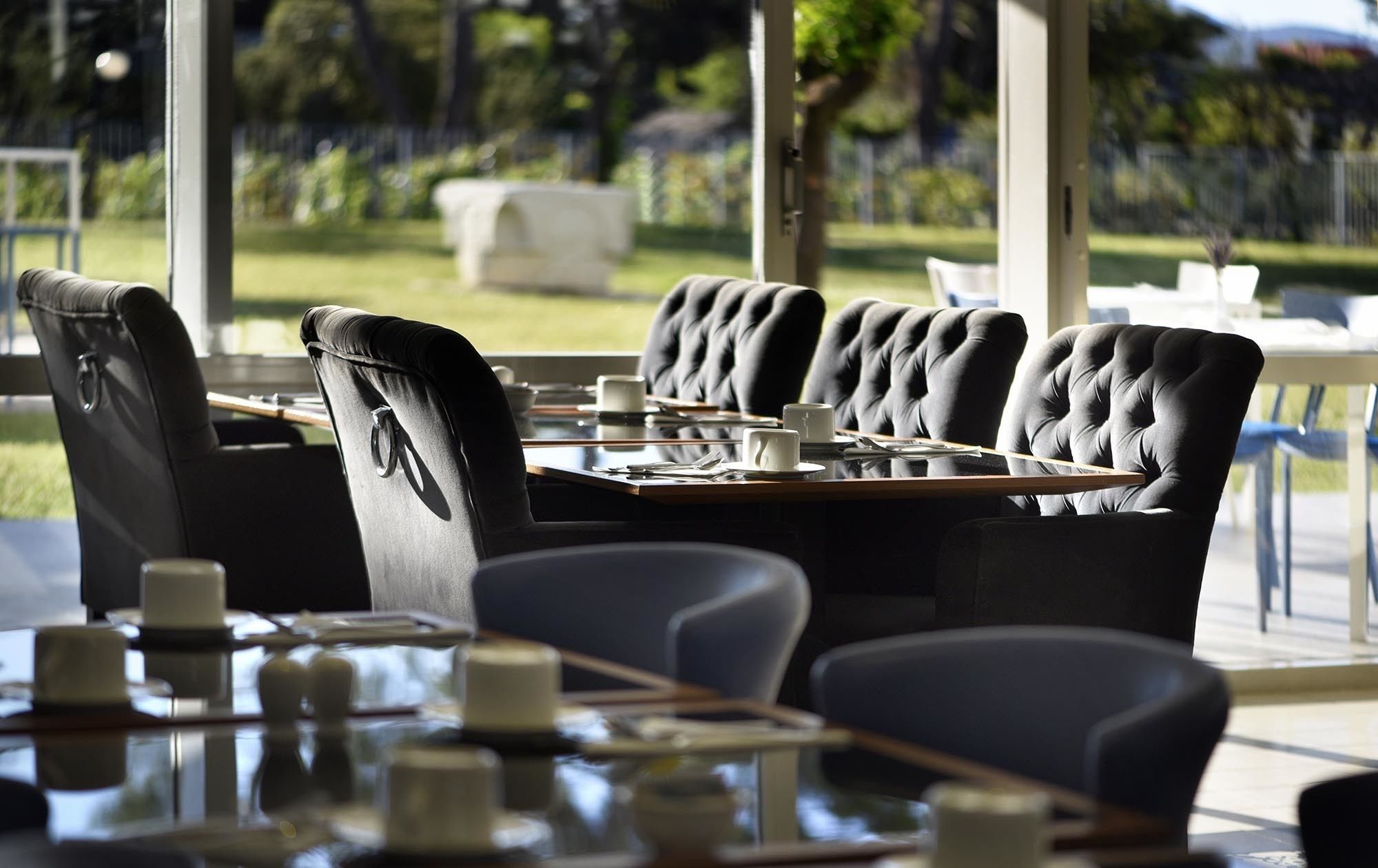 A restaurant with black upholstered chairs and a glass table.