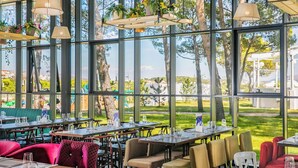 Ein Restaurant mit großen Fenstern, Außenbereich und hängenden Pflanzen.