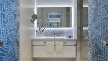A modern bathroom with a marble vanity, a large mirror, and a glass shower enclosure.