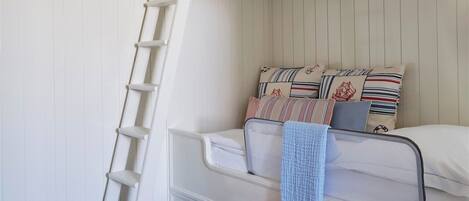 A bunk bed with a ladder, a checkered floor, and a patterned ottoman.
