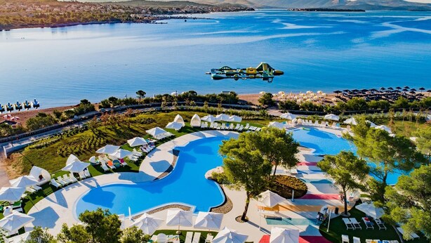 Un resort con varias piscinas, una zona de playa y vistas al mar.