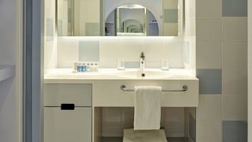 A modern bathroom with a white sink, mirror, and tiled walls.