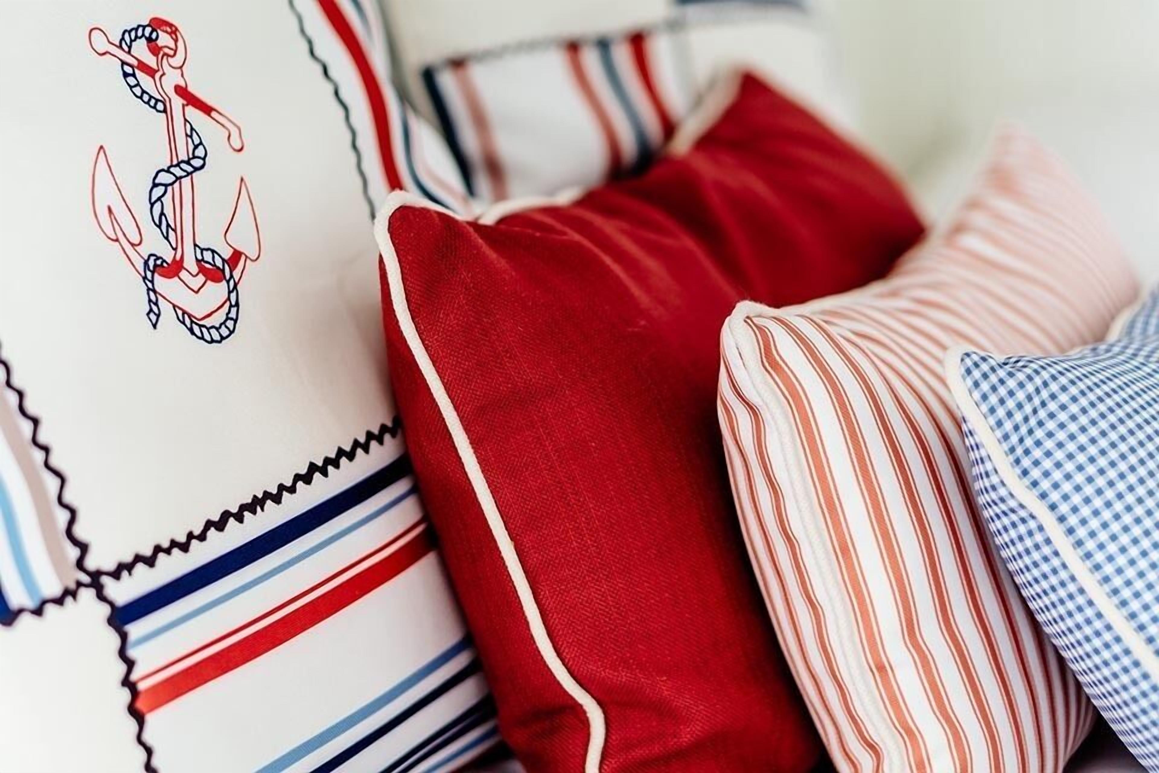 A close-up of a bed with striped bedding and a pillow with a nautical anchor design.