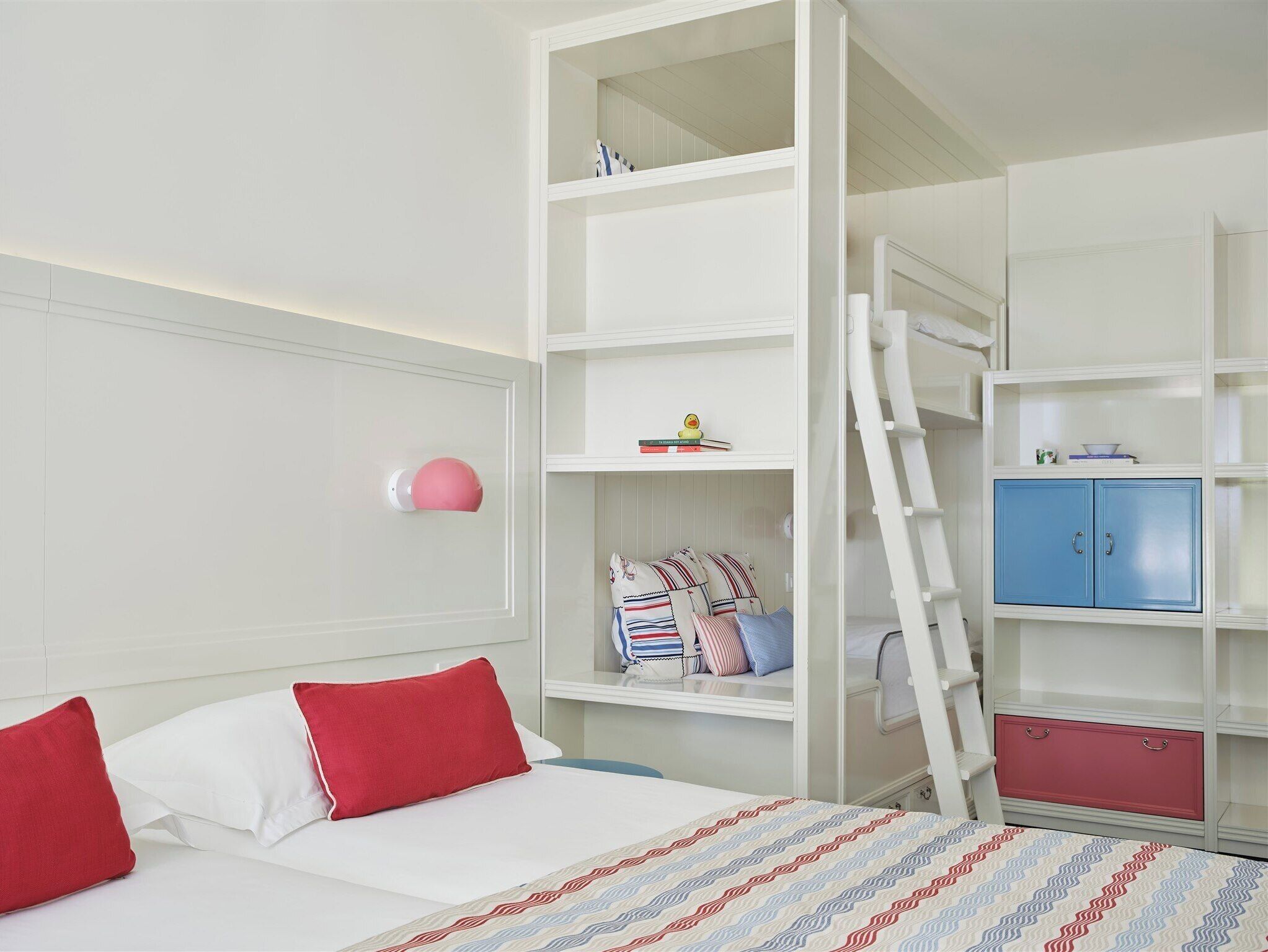 Une chambre à coucher avec un lit, une armoire blanche, une commode bleue et une échelle.