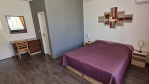 Un dormitorio con una cama, un escritorio, una silla y una obra de arte colgada en la pared.